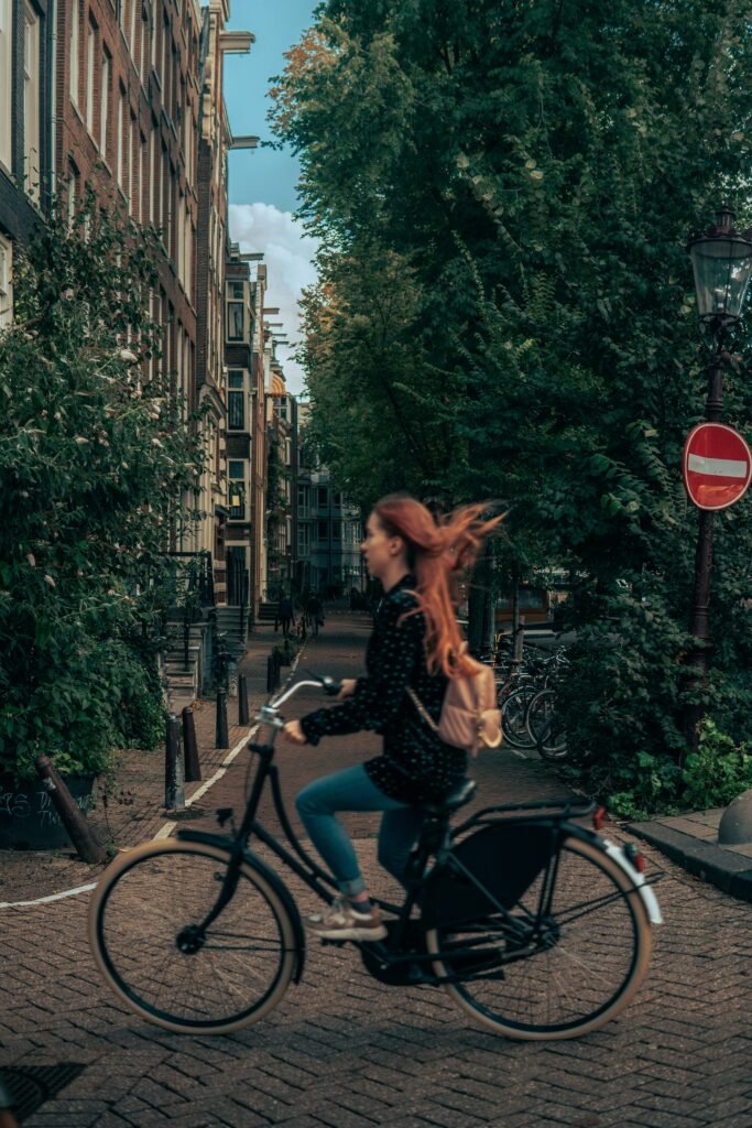 A woman is biking in the streets of a European city. Her bike is vintage. She is blurred because of her speed.