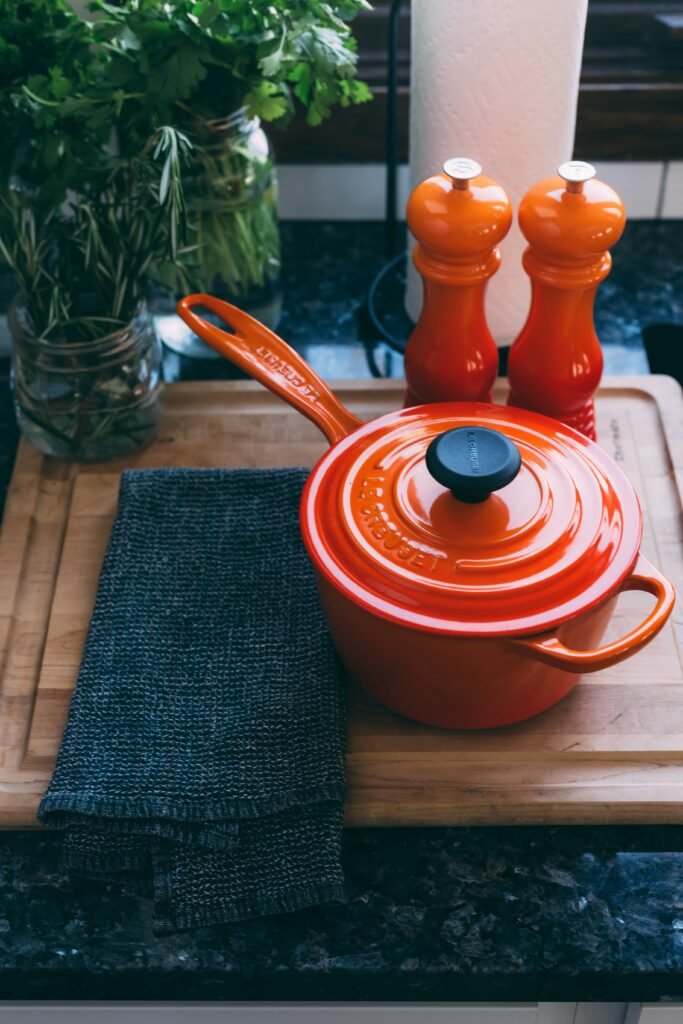 A red pot on the counter with red salt and pepper shakers