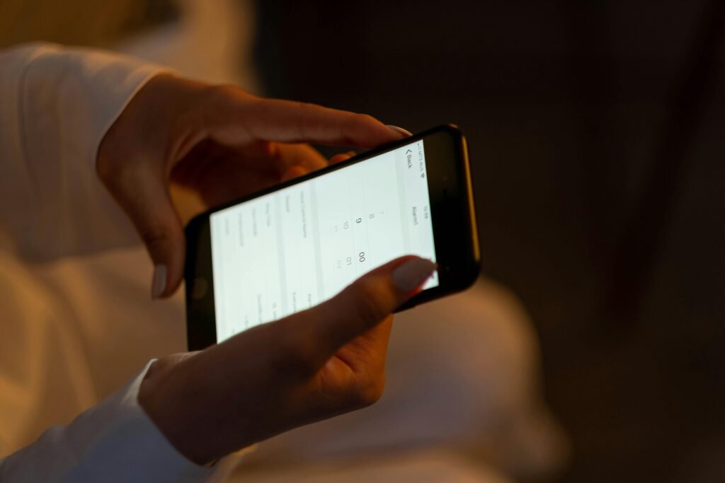Close-up of hands setting an alarm on a smartphone, depicting night usage and technology interaction.